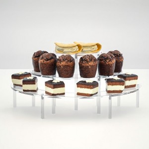 The transparent pastry stand elegantly showcases mini cupcakes and cream puffs at a wedding reception